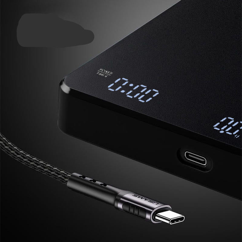 A close-up of a black USB-C charging device with a digital display showing 0:00, connected to a braided black cable with a USB-C connector.
