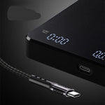 A close-up of a black USB-C charging device with a digital display showing 0:00, connected to a braided black cable with a USB-C connector.